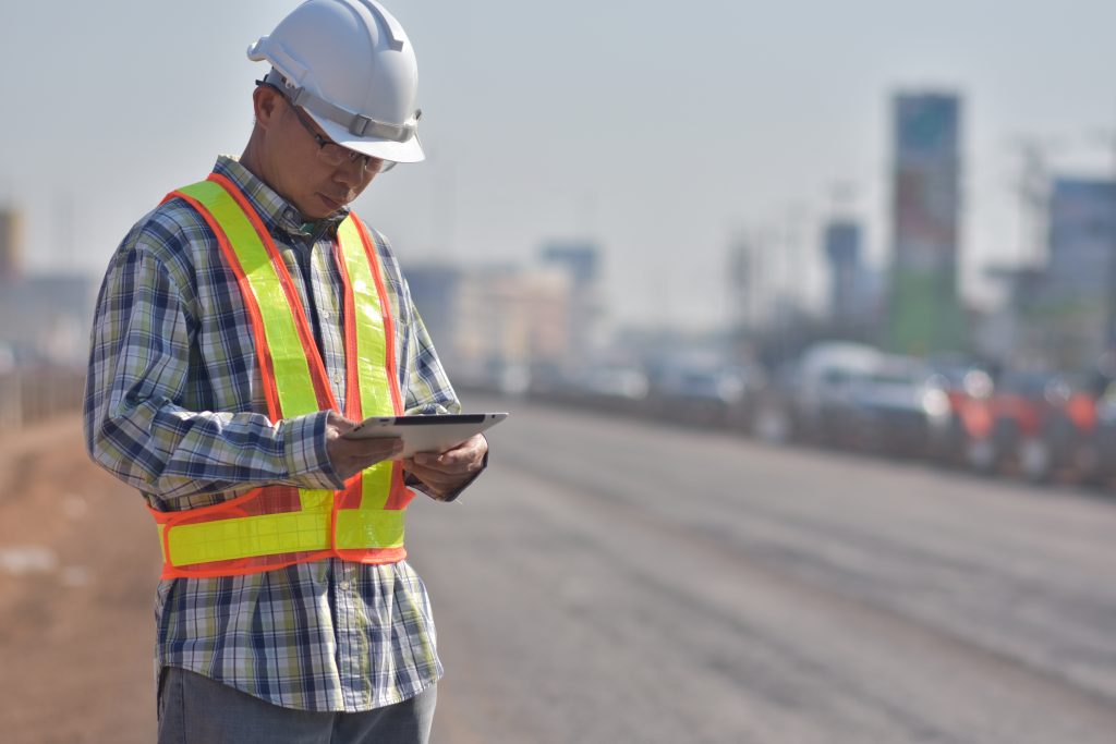 Senior Engineering holding tablet data technology working on road construction site