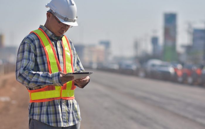 Senior Engineering holding tablet data technology working on road construction site