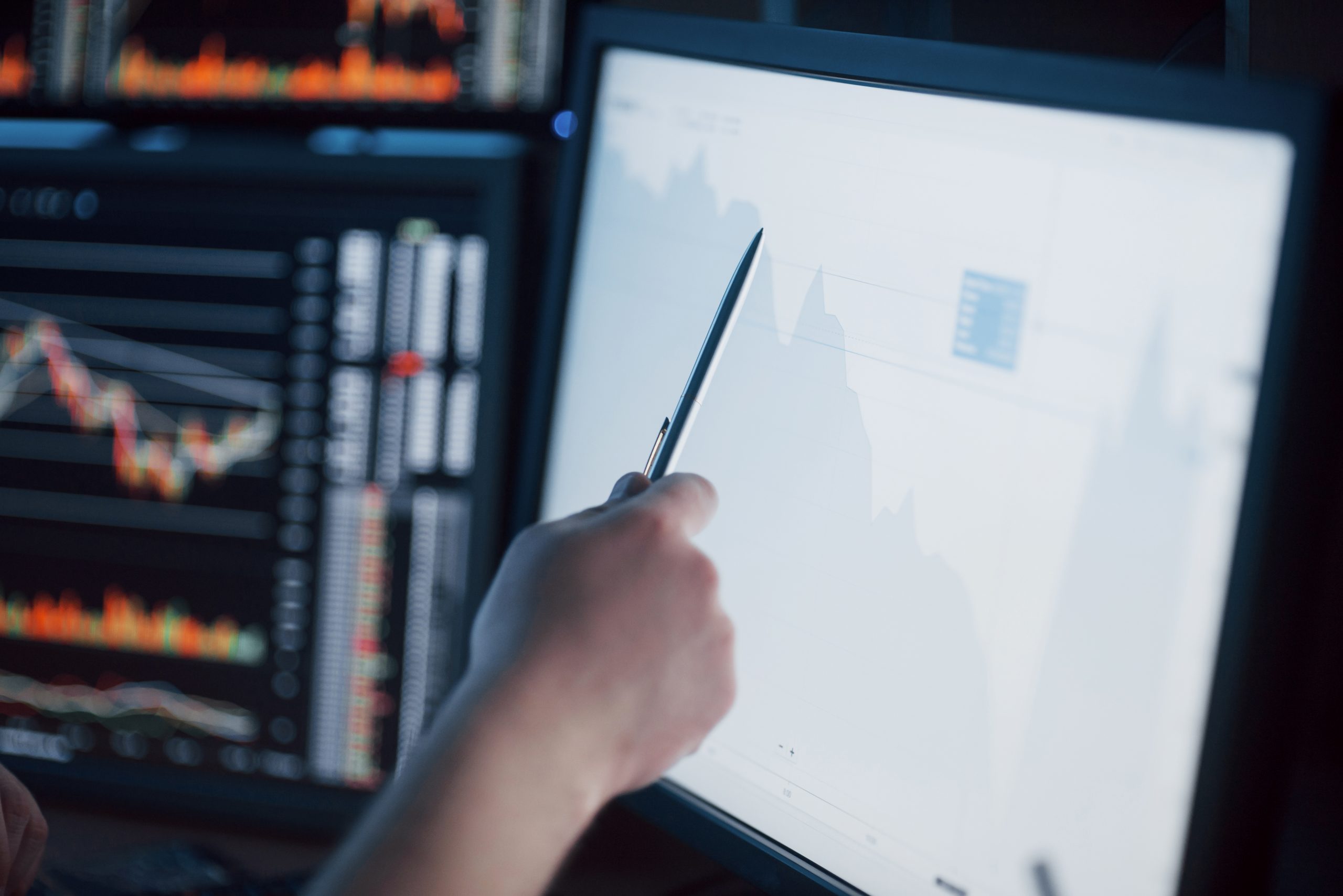 Analyzing data. Close-up of young businessman pointing on the data presented in the chart with pen while working in creative office