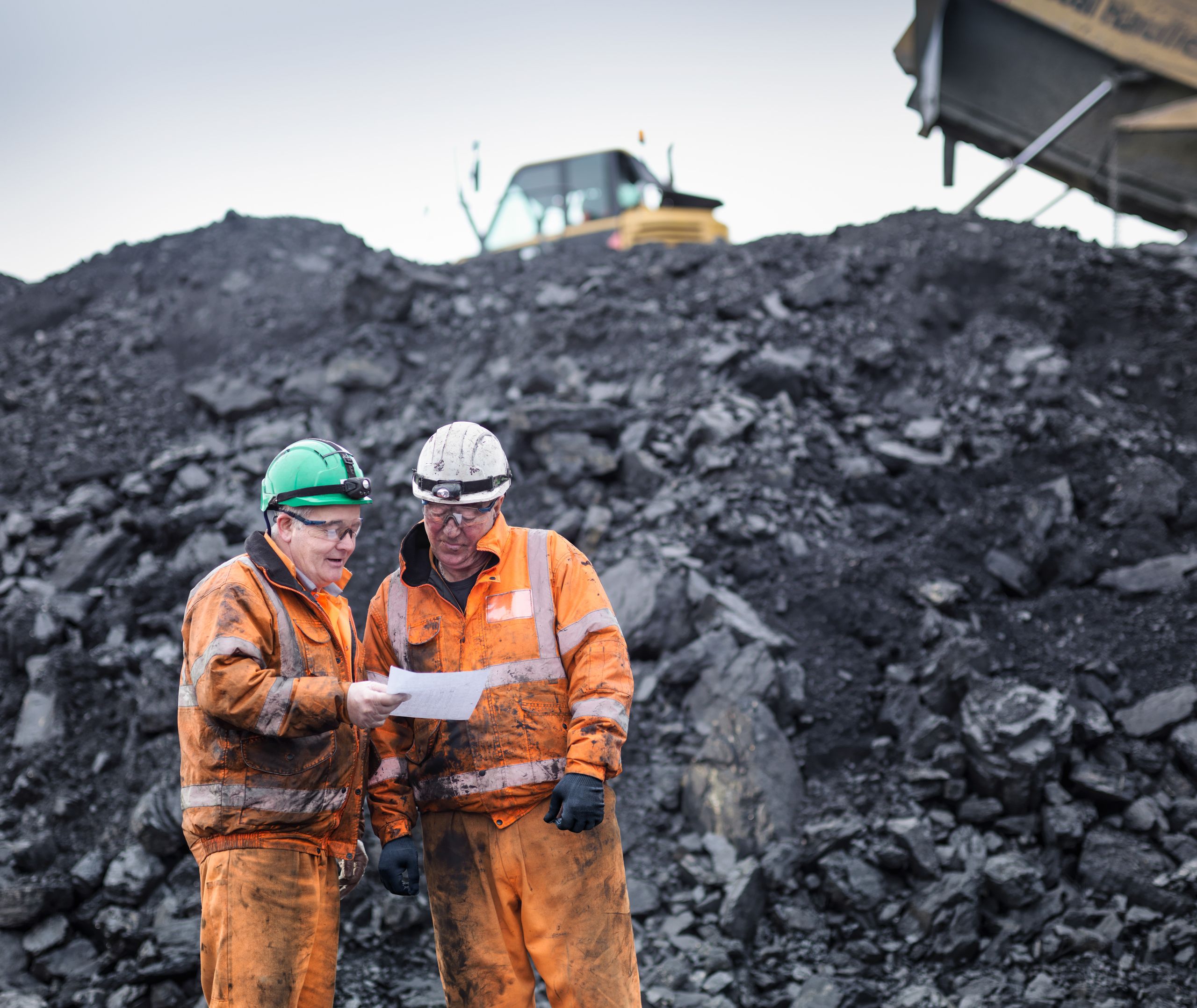 mining workers in discussion in front of coal stocks