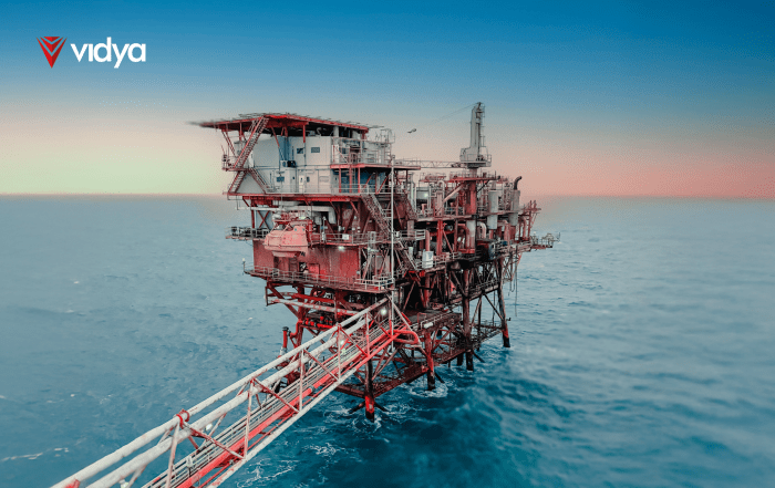 Offshore oil and gas platform standing in open sea at sunset, with visible structural details and a connected access bridge, branded with the Vidya logo.